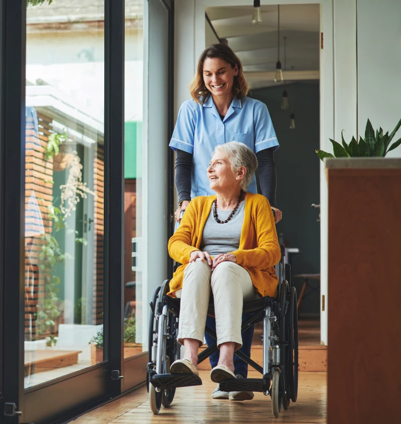 Nurse pushing wheelchair indoors