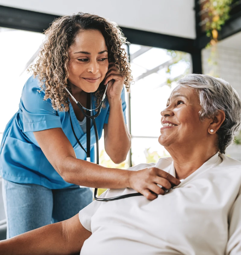 Nurse checking senior woman's heart with stethoscope